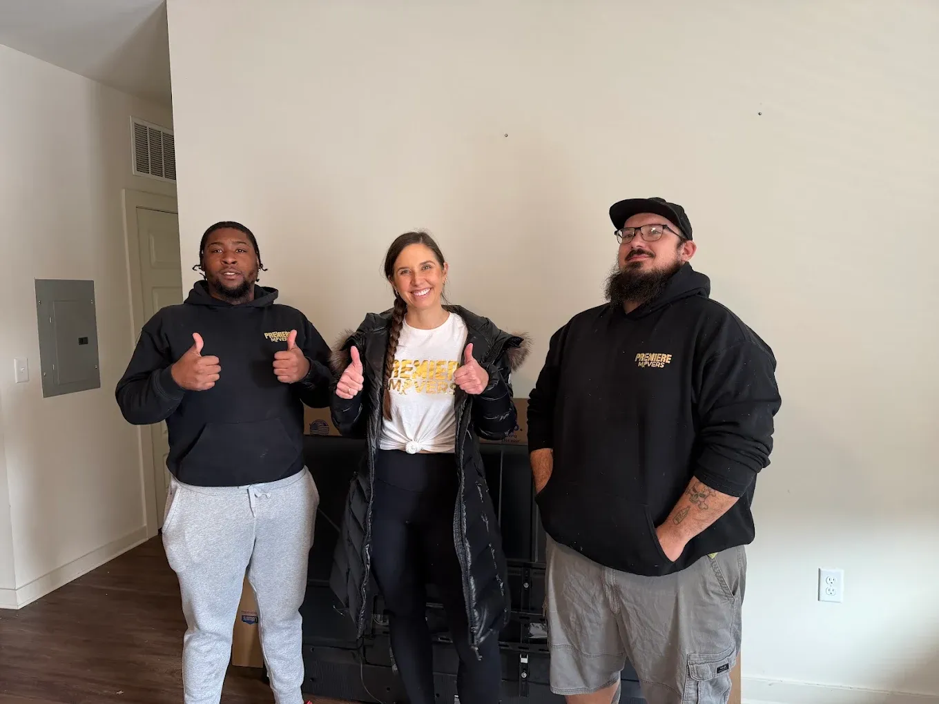 Three Premiere Movers crew members in branded shirts in a cleared room at the end of a move