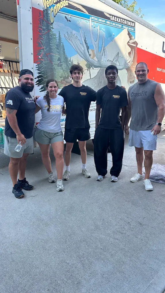 The Premiere Movers crew of five in branded shirts standing in front of a moving truck