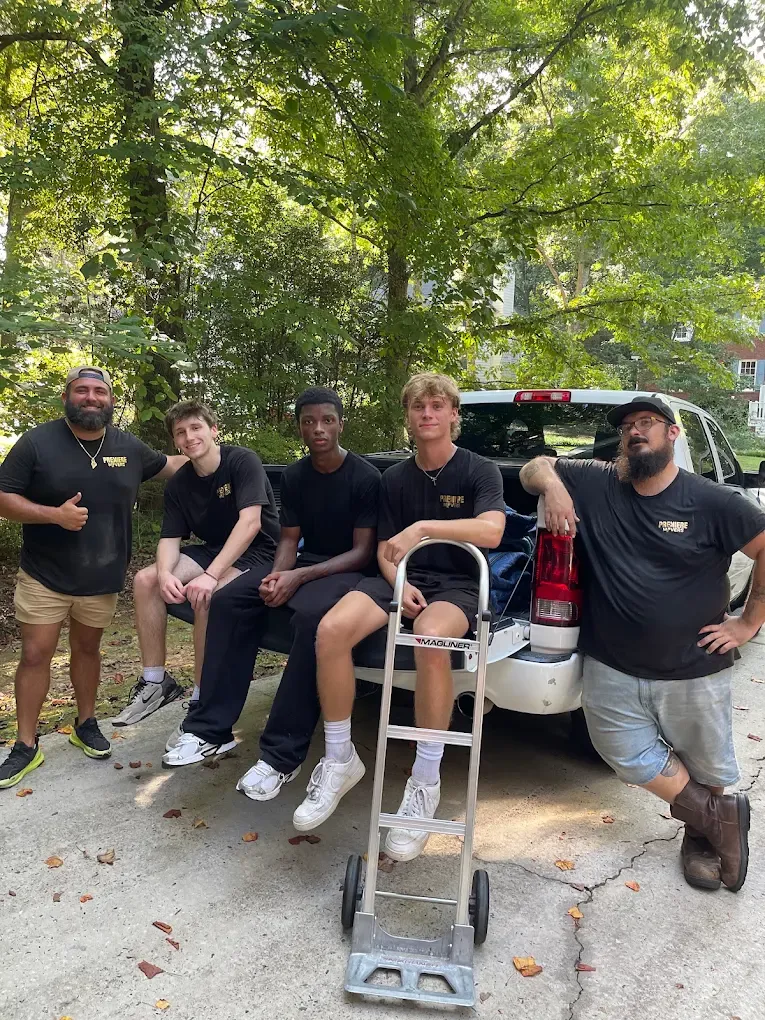 Five Premiere Movers crew members with a hand truck on a tree lined north Georgia street